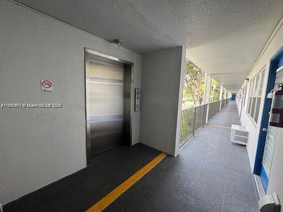 Exterior view of an elevator area on a building floor with a hallway and railings.