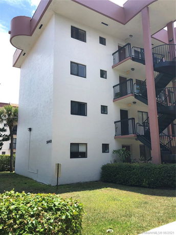 Front view of a multi-story residential building with external staircases and balconies.