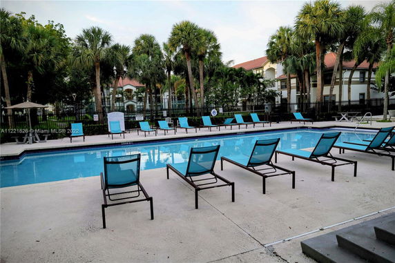 Outdoor swimming pool area with lounge chairs and palm trees in the background.