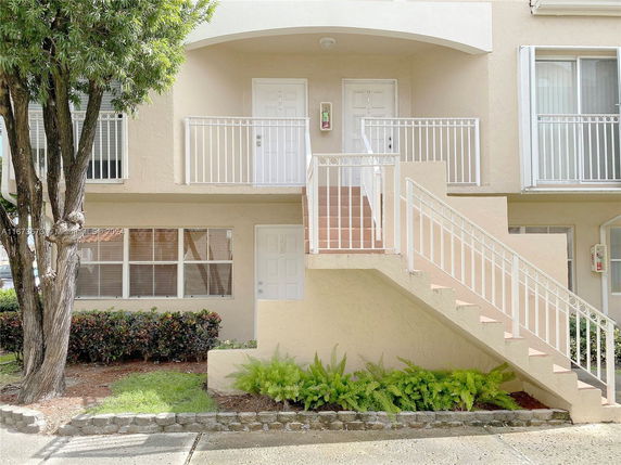 Front view of a two-story building with exterior stairs and multiple doors.
