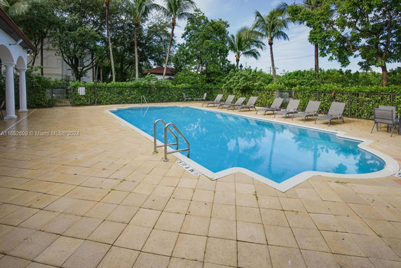 Outdoor swimming pool with surrounding lounge chairs and palm trees.