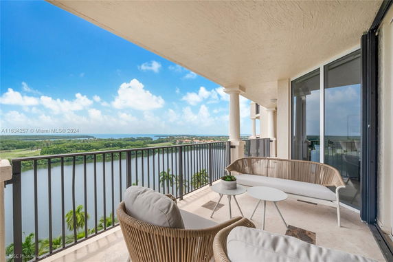 Balcony with outdoor furniture overlooking a scenic view of water and greenery.