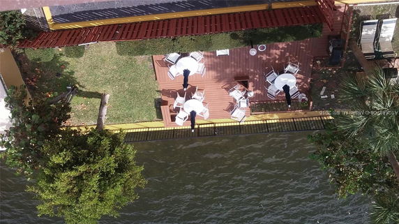 Rooftop view with patio furniture and umbrellas near a water body.