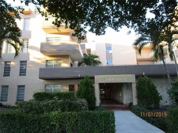 Front view of a multi-story residential building with balconies and a covered entrance.