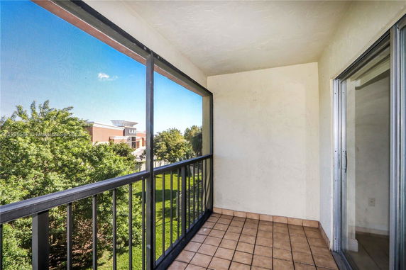 Balcony with a view of the surrounding trees and a building in the distance.