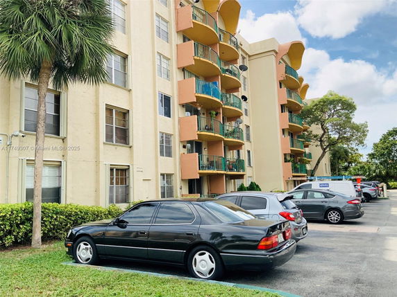 Outdoor parking area in front of a multi-story residential building with balconies.