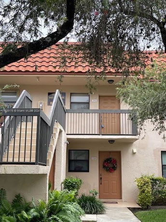 Front view of a two-story residential building with external stairs and a balcony.