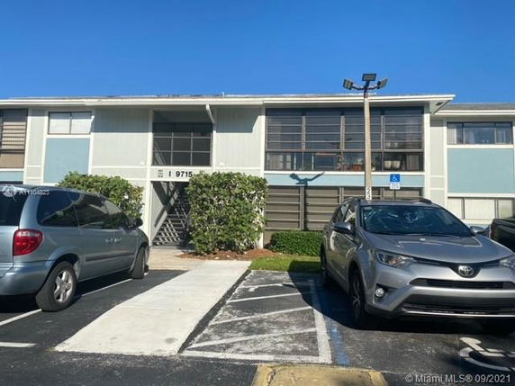 Front view of a two-story residential building with a parking area in front.