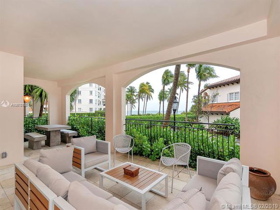 Outdoor seating area with views of palm trees and nearby buildings.