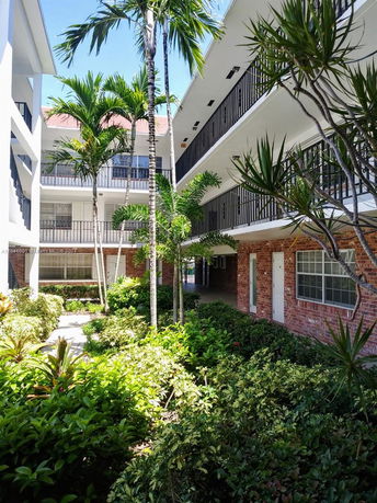 View of a multi-story apartment building with a garden courtyard.