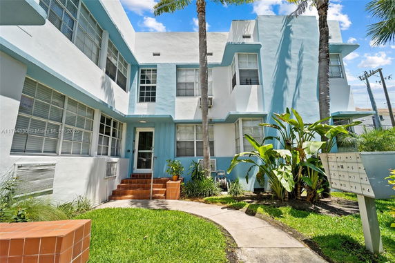 Front view of a light blue and white apartment building with multiple windows.