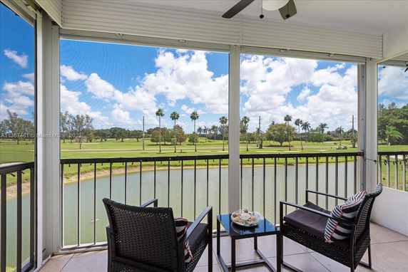 View from a balcony overlooking a golf course with a lake and palm trees.