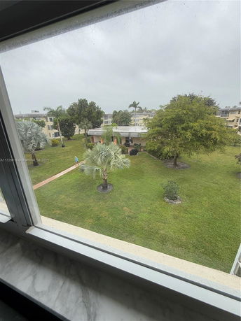 View of multiple residential buildings and landscaped garden area seen from a window.