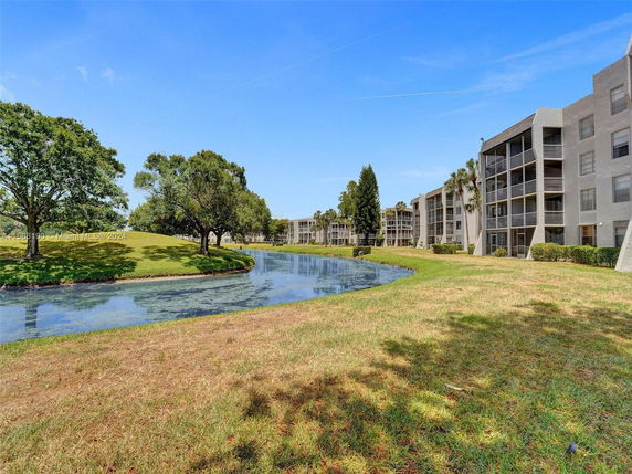 View of residential buildings and a waterway with trees and grass.