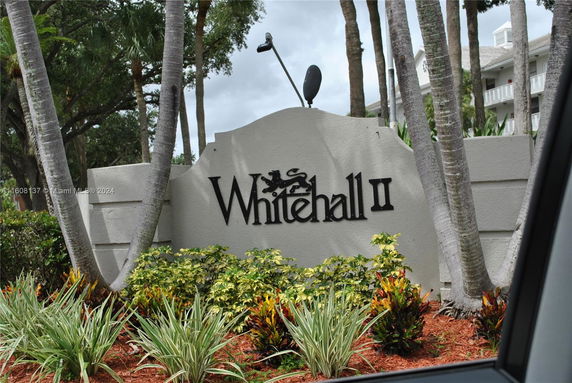 Sign for Whitehall II surrounded by palm trees and landscaping.