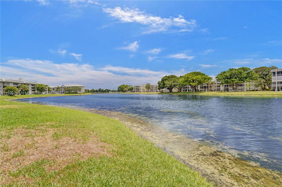 Panoramic view of a lake surrounded by residential buildings and trees.
