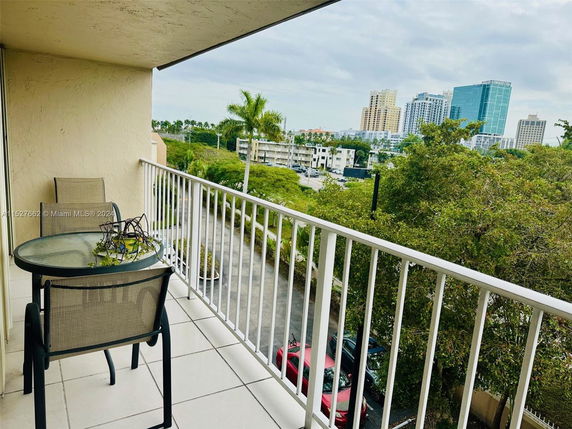 Balcony view overlooking city buildings and trees.