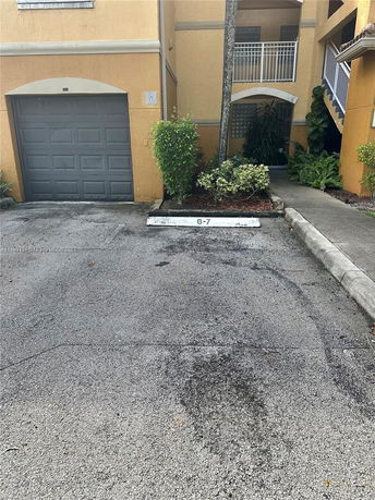 Outdoor parking area in front of a building with a garage door.