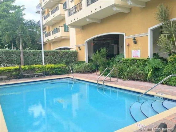 Front view of a multi-story building with balconies overlooking a swimming pool area.