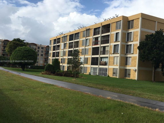 Front view of a multi-story apartment building with yellow and white exterior.