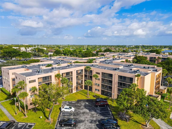 Front view of a multi-story residential building complex with parking area.