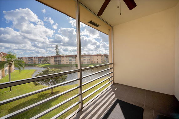 Balcony view overlooking a pond and nearby residential buildings.