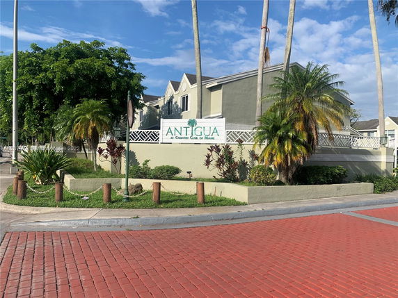 Front view of a residential building with a sign reading 'Antigua at Country Club of Miami.'