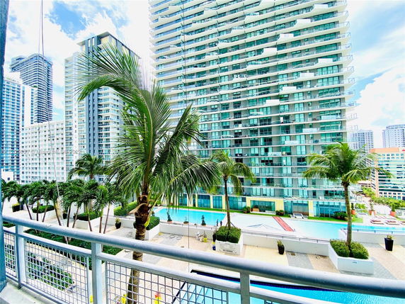View of modern high-rise buildings with balconies and a swimming pool in a city setting.