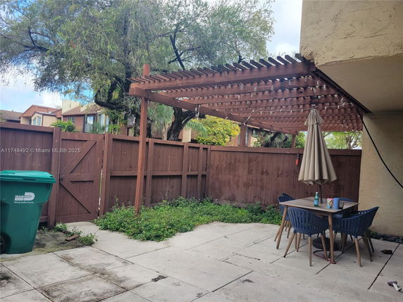 Outdoor patio with pergola and patio furniture in a fenced yard.