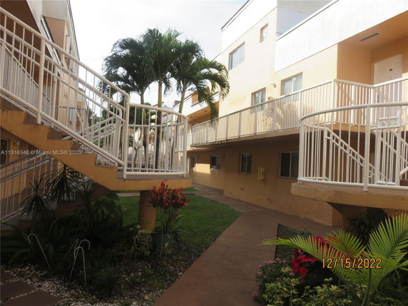 Outdoor view of a multi-level residential building with exterior staircases and greenery.