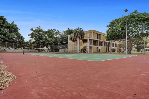 View of a tennis court with a building in the background.