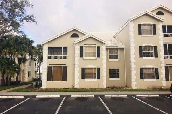 Front view of a multi-story residential building with parking spaces in front.