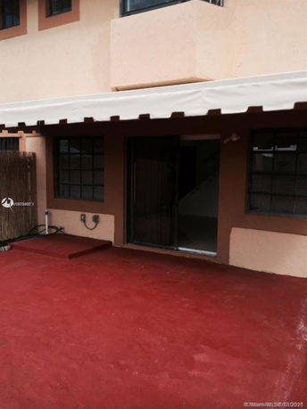 Front view of a building with sliding glass doors and a red paved area.