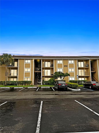 Front view of a three-story apartment building with assigned parking spaces in front.