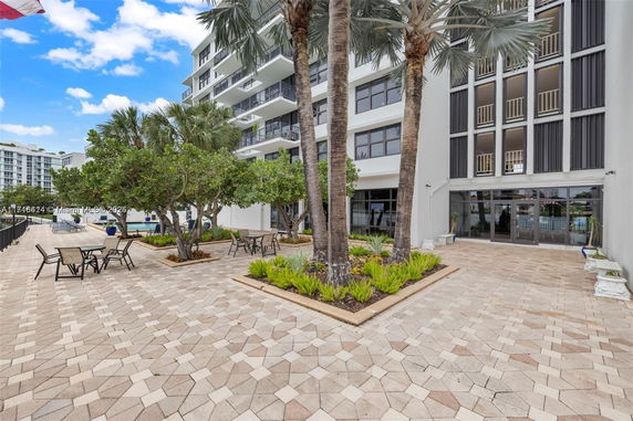Front view of a multi-story building with a landscaped courtyard and patio furniture.