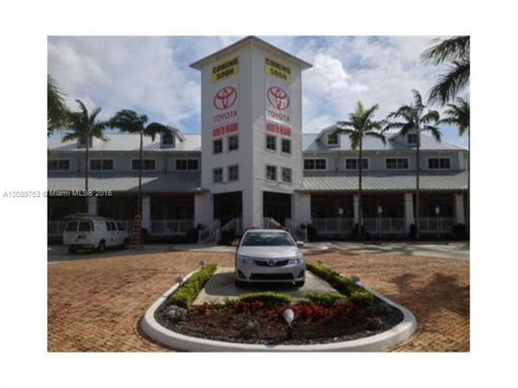 Front view of a multi-story building with automotive dealership banners.