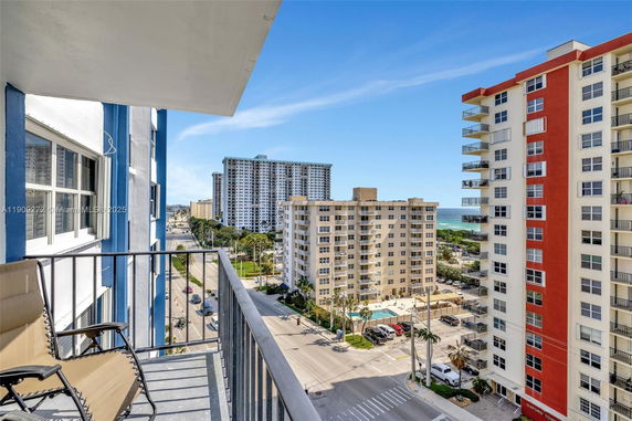 Panoramic view from a balcony overlooking multiple high-rise buildings near the coast.