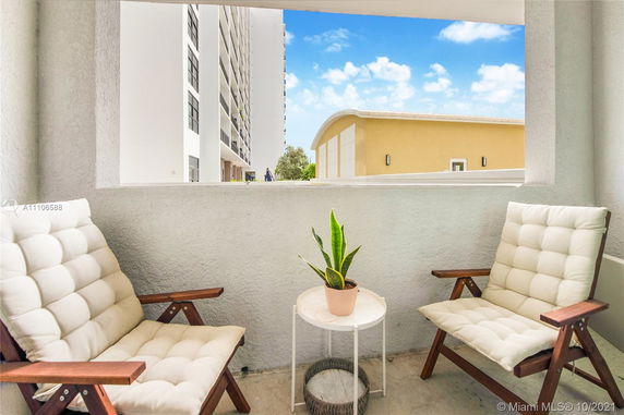 View from a balcony with two cushioned chairs and a small table with a plant.