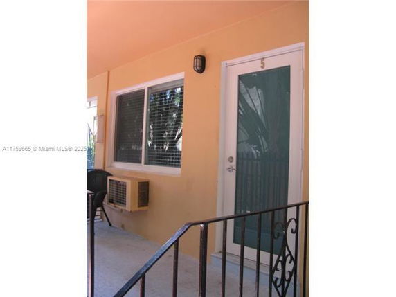 Front view of a unit with a door and window, featuring an external air conditioning unit.