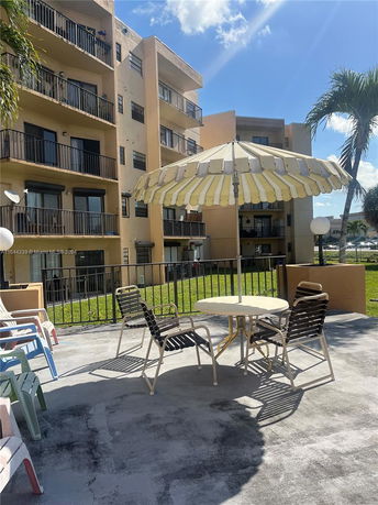View of a multi-story apartment building exterior with balconies and outdoor seating area.