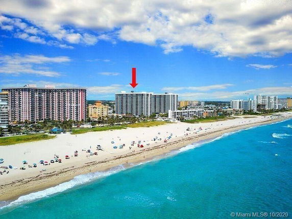 View of beachfront high-rise buildings with a sandy shore and ocean.