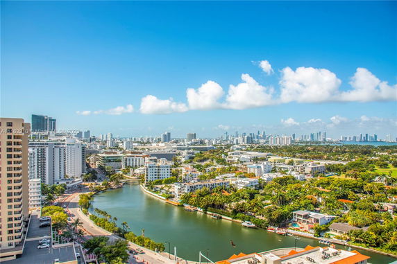 Panoramic view of a cityscape with high-rise buildings, a waterway, and distant skyline.