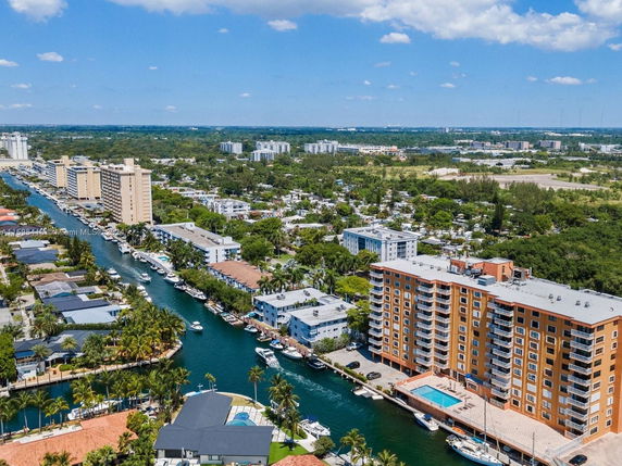 Aerial view of residential buildings along a canal with boats and trees.