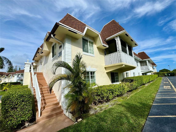 Front view of a two-story residential building with multiple units and a staircase leading to the upper floor.
