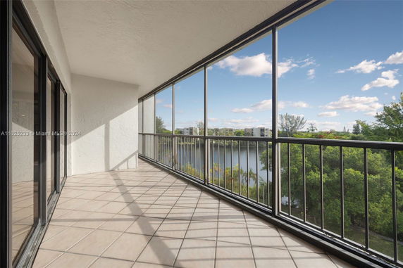 Panoramic view from a balcony showing surrounding greenery and buildings in the distance.