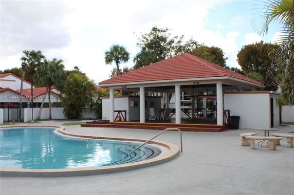 Outdoor swimming pool with a covered seating area nearby.
