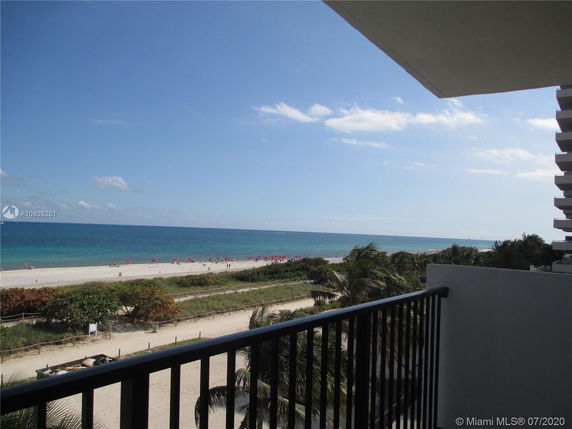 View from a building balcony overlooking a beach and ocean.