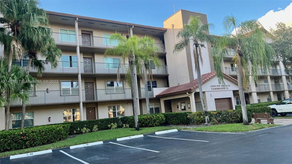 Front view of a multi-story apartment building with balconies and palm trees.