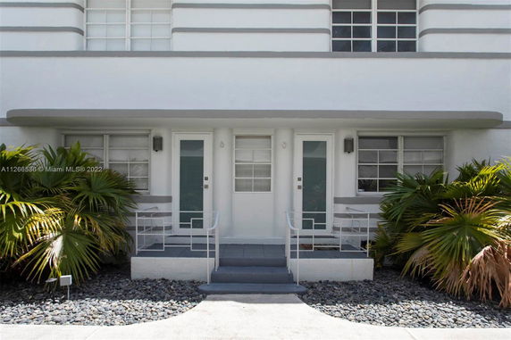 Front view of a building with two identical doors and decorative plants.