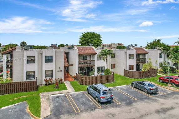 Front view of a multi-story residential building with a parking area.